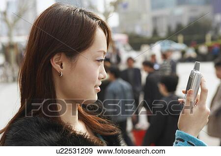 Side profile of a young woman looking at a mobile phone View Large Photo Image Stock Photo - Side profile of a young woman looking at a mobile phone. Fotosearch