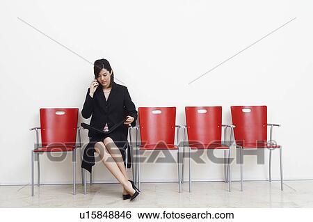 Businesswoman holding a file and talking on a mobile phone View Large Photo Image Stock Photograph - Businesswoman holding a file and talking on a mobile phone. Fotosearch