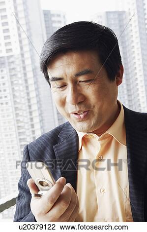 Stock Image - Close-up of a businessman looking at a mobile phone. Fotosearch