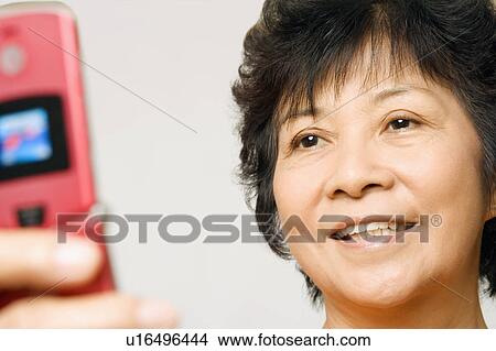 Close-up of a mature woman holding a mobile phone View Large Photo Image Picture - Close-up of a mature woman holding a mobile phone. Fotosearch