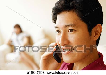 Close-up of a young man talking on a mobile phone and smiling View Large Photo Image Stock Photo - Close-up of a young man talking on a mobile phone and smiling. Fotosearch