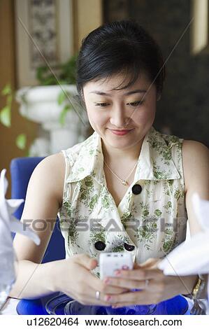 Close-up of a young woman holding a mobile phone View Large Photo Image Picture - Close-up of a young woman holding a mobile phone. Fotosearch