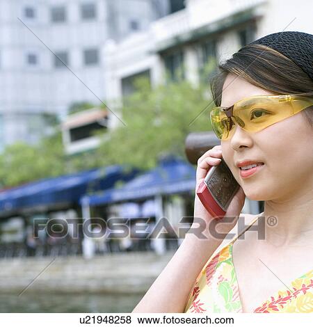 Close-up of a young woman talking on a mobile phone View Large Photo Image Stock Photo - Close-up of a young woman talking on a mobile phone. Fotosearch