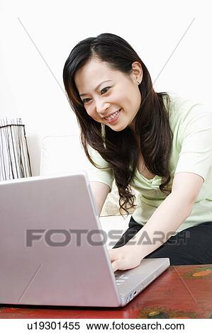 Close-up of a young woman using a laptop and smiling View Large Photo Image Stock Photography - Close-up of a young woman using a laptop and smiling. Fotosearch