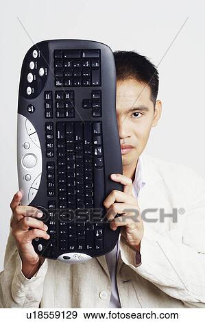 Portrait of a businessman holding a computer keyboard in front of his face View Large Photo Image Stock Photo - Portrait of a businessman holding a computer keyboard in front of his face. Fotosearch