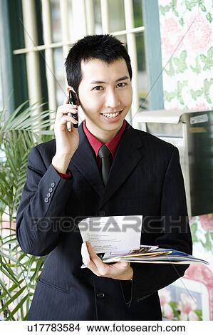 Portrait of a businessman holding paper and talking on a mobile phone View Large Photo Image Picture - Portrait of a businessman holding paper and talking on a mobile phone. Fotosearch
