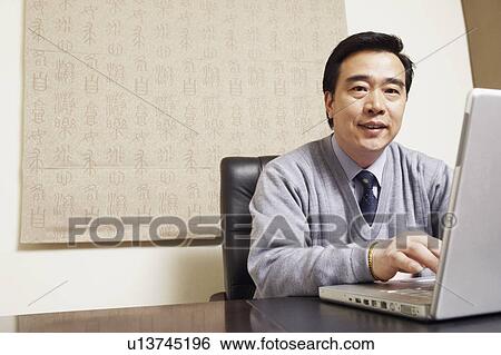 Portrait of a businessman using a laptop View Large Photo Image Stock Photograph - Portrait of a businessman using a laptop. Fotosearch