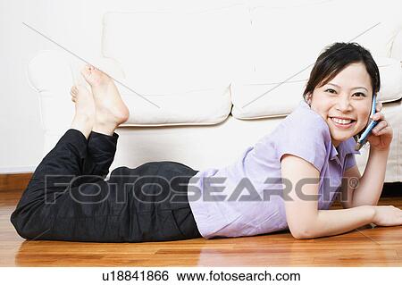 Portrait of a young woman lying on the floor and talking on a mobile phone View Large Photo Image Stock Photograph - Portrait of a young woman lying on the floor and talking on a mobile phone. Fotosearch