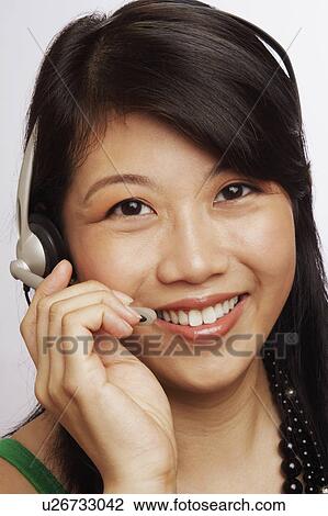 Portrait of a young woman smiling and wearing a headset View Large Photo Image Stock Image - Portrait of a young woman smiling and wearing a headset. Fotosearch