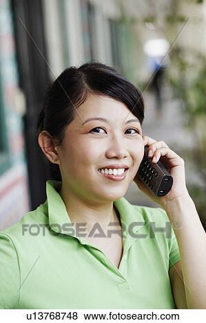 Stock Photo - Portrait of a young woman talking on a cordless phone. Fotosearch