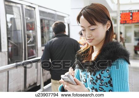 Side profile of a young woman operating a mobile phone with a digitized pen View Large Photo Image Picture - Side profile of a young woman operating a mobile phone with a digitized pen. Fotosearch