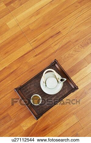 Picture - High angle view of a teapot and a tea cup with a tray on a hardwood floor. Fotosearch