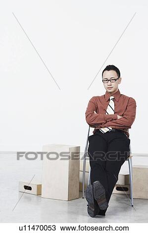 Portrait of a businessman sitting on a chair View Large Photo Image Stock Image - Portrait of a businessman sitting on a chair. Fotosearch