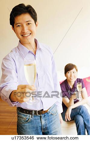 Stock Photograph - Portrait of a young man smiling and holding a champagne flute. Fotosearch