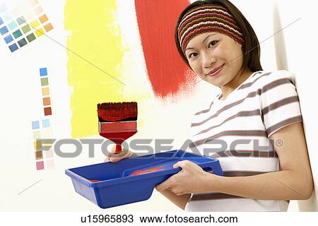 Portrait of a young woman holding a paint tray with a paintbrush and smiling View Large Photo Image Stock Image - Portrait of a young woman holding a paint tray with a paintbrush and smiling. Fotosearch