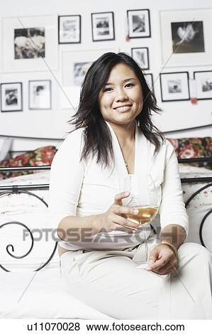 Stock Photo - Portrait of a young woman holding a glass of wine. Fotosearch