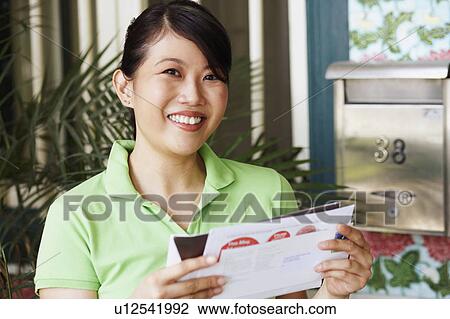 Portrait of a young woman holding mails and smiling View Large Photo Image Stock Image - Portrait of a young woman holding mails and smiling. Fotosearch