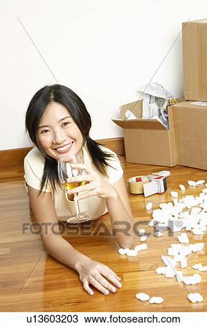 Portrait of a young woman lying on the floor and holding a glass of wine View Large Photo Image Stock Image - Portrait of a young woman lying on the floor and holding a glass of wine. Fotosearch