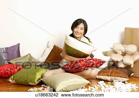 Portrait of a young woman sitting on the floor and hugging a cushion View Large Photo Image Stock Image - Portrait of a young woman sitting on the floor and hugging a cushion. Fotosearch