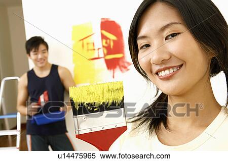 Portrait of a young woman smiling with a young man standing in the background View Large Photo Image Stock Photography - Portrait of a young woman smiling with a young man standing in the background. Fotosearch