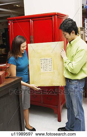 Young couple holding a painting and smiling View Large Photo Image Stock Photo - Young couple holding a painting and smiling. Fotosearch