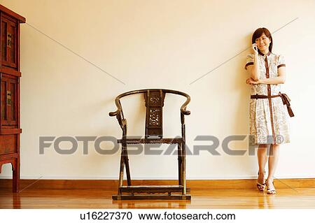 Young woman leaning against a wall and talking on a mobile phone View Large Photo Image Stock Image - Young woman leaning against a wall and talking on a mobile phone. Fotosearch