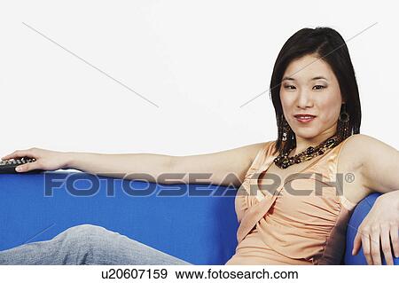 Stock Photo - Young woman sitting on a couch. Fotosearch