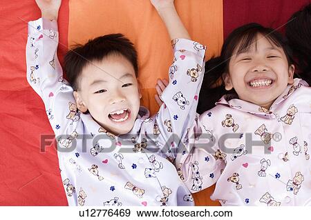 Close-up of a boy and a girl lying on the bed and looking cheerful View Large Photo Image Stock Photo - Close-up of a boy and a girl lying on the bed and looking cheerful. Fotosearch