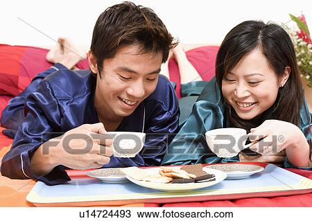 Close-up of a mid adult man holding a cup and lying on the bed with a young woman View Large Photo Image Stock Image - Close-up of a mid adult man holding a cup and lying on the bed with a young woman. Fotosearch