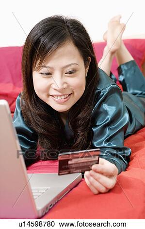 Stock Image - Close-up of a young woman holding a credit card. Fotosearch