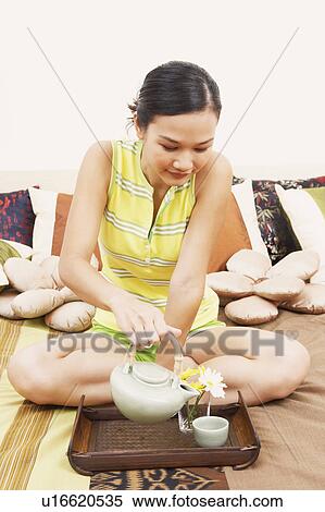 Close-up of a young woman pouring tea from a tea kettle into the cup View Large Photo Image Stock Photography - Close-up of a young woman pouring tea from a tea kettle into the cup. Fotosearch