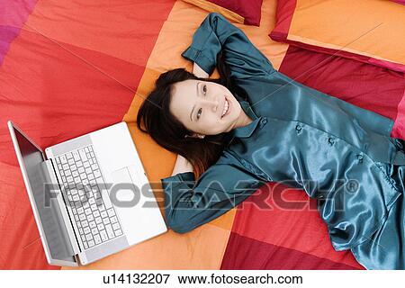 Stock Photo - High angle view of a young woman lying on the bed. Fotosearch