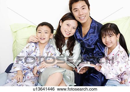Portrait of a boy and a girl smiling with their parents on the bed View Large Photo Image Stock Photograph - Portrait of a boy and a girl smiling with their parents on the bed. Fotosearch