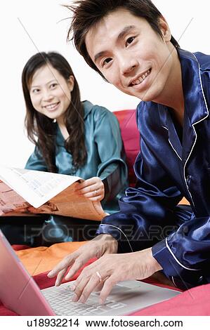 Portrait of a mid adult man using a laptop and young woman reading a newspaper View Large Photo Image Picture - Portrait of a mid adult man using a laptop and young woman reading a newspaper. Fotosearch
