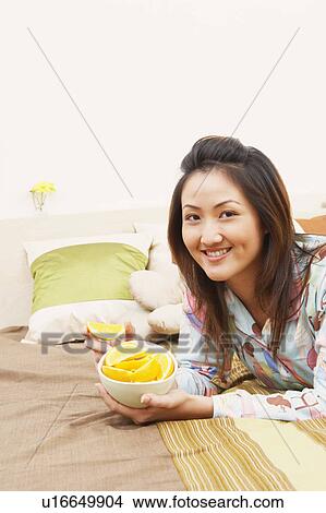 Portrait of a young woman holding a bowl of lemon slices and smiling View Large Photo Image Picture - Portrait of a young woman holding a bowl of lemon slices and smiling. Fotosearch