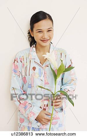 Stock Image - Portrait of a young woman holding a flower. Fotosearch
