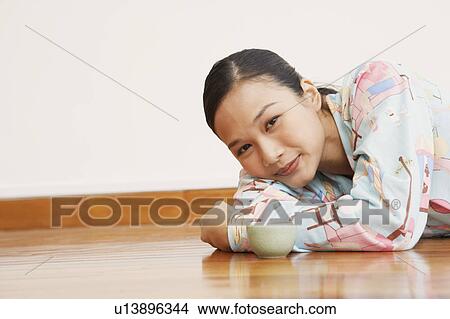 Portrait of a young woman lying in front of a tea cup View Large Photo Image Picture - Portrait of a young woman lying in front of a tea cup. Fotosearch