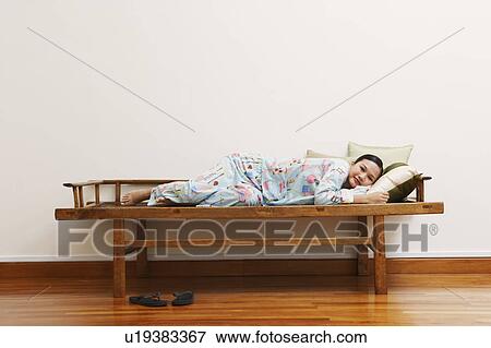 Portrait of a young woman lying on a bench and smiling View Large Photo Image Stock Photo - Portrait of a young woman lying on a bench and smiling. Fotosearch
