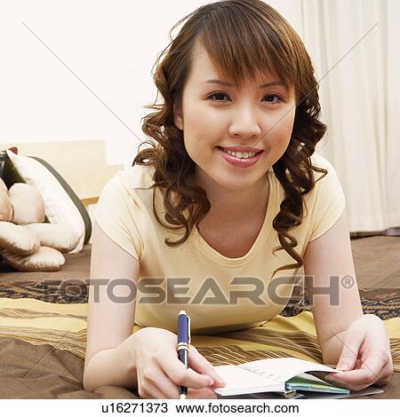 Portrait of a young woman lying on the bed and smiling View Large Photo Image Stock Image - Portrait of a young woman lying on the bed and smiling. Fotosearch