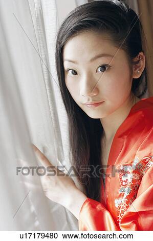 Portrait of a young woman standing near a window View Large Photo Image Stock Image - Portrait of a young woman standing near a window. Fotosearch