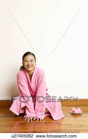 Stock Image - Young woman sitting on the floor with a plate of soap beside her. Fotosearch