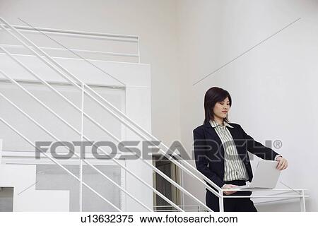 Stock Photography - Businesswoman using a laptop on a staircase. Fotosearch