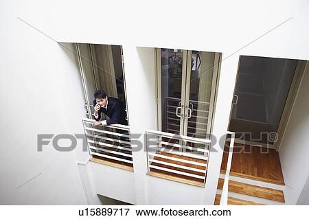 High angle view of a businessman standing at the doorway in an office and talking on a mobile phone View Large Photo Image Stock Photo - High angle view of a businessman standing at the doorway in an office and talking on a mobile phone. Fotosearch