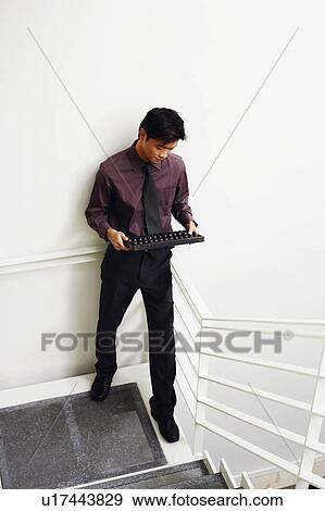 High angle view of a businessman standing on a staircase and holding an abacus View Large Photo Image Stock Photo - High angle view of a businessman standing on a staircase and holding an abacus. Fotosearch