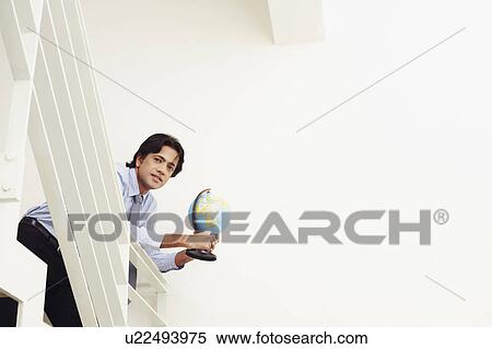 Low angle view of a businessman leaning over a railing and holding a globe View Large Photo Image Stock Photography - Low angle view of a businessman leaning over a railing and holding a globe. Fotosearch
