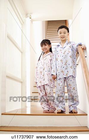Stock Photo - Portrait of a boy standing with his sister near a staircase. Fotosearch