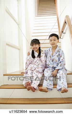 Portrait of a boy with a girl sitting in front of a staircase View Large Photo Image Picture - Portrait of a boy with a girl sitting in front of a staircase. Fotosearch