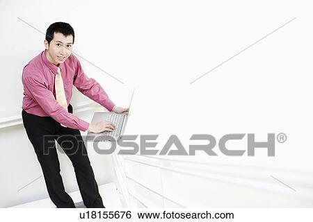 Portrait of a businessman using a laptop on a railing View Large Photo Image Stock Photograph - Portrait of a businessman using a laptop on a railing. Fotosearch