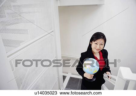 Portrait of a businesswoman holding a globe and smiling View Large Photo Image Stock Image - Portrait of a businesswoman holding a globe and smiling. Fotosearch