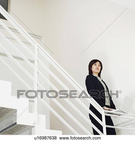 Portrait of a businesswoman holding a laptop on the staircase View Large Photo Image Stock Photo - Portrait of a businesswoman holding a laptop on the staircase. Fotosearch